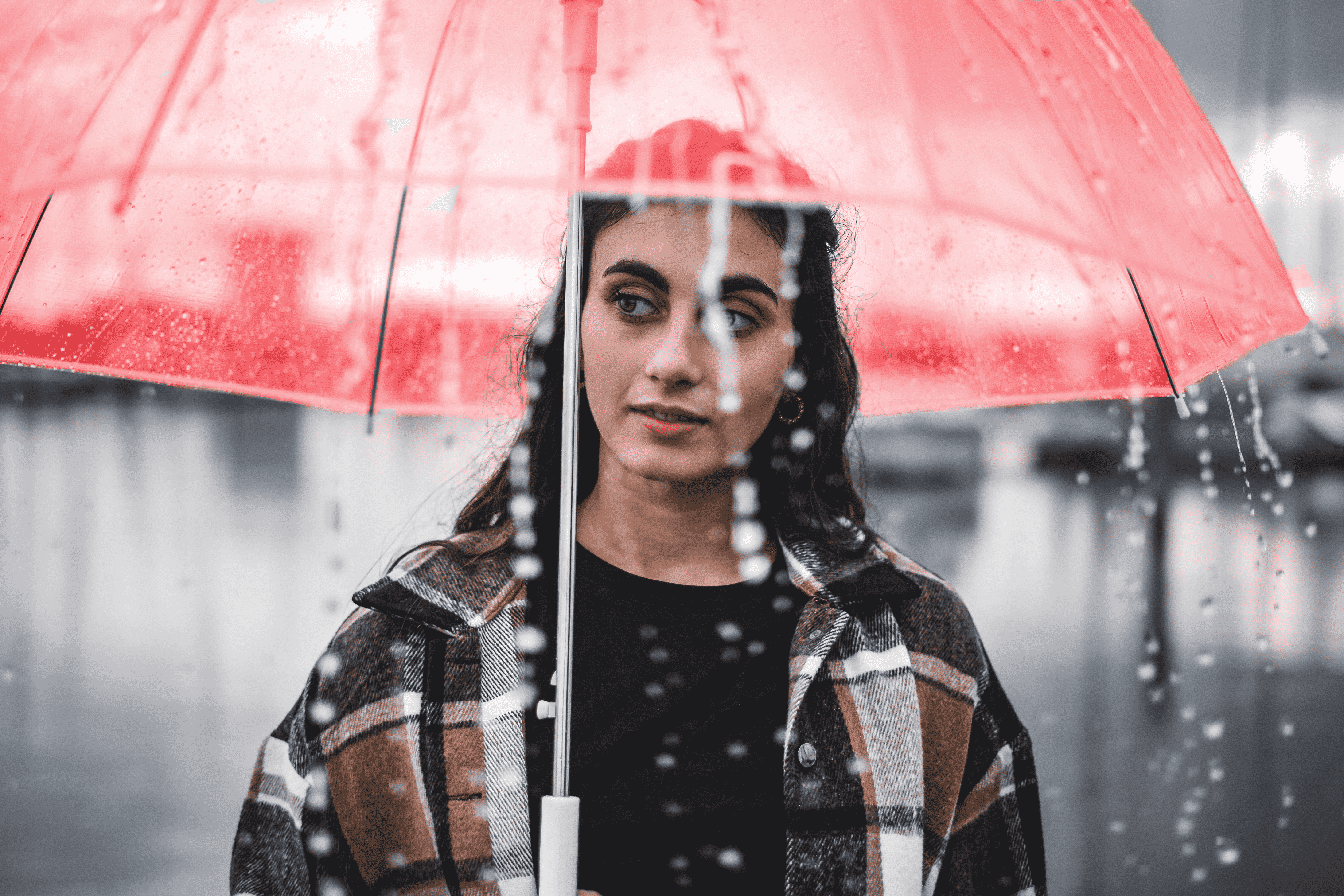 Photo of a young woman holding a red umbrella. The red umbrella is a symbol for sex work, embraced by sex workers. 