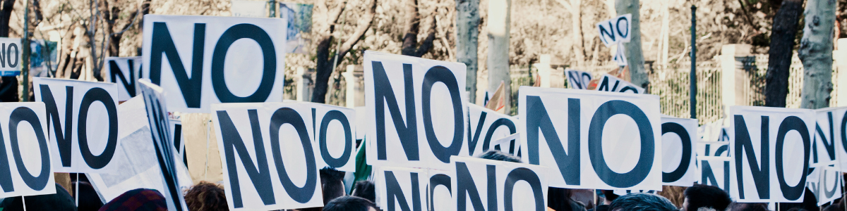 A photo of a protest group, all holding signs that have "no" written in big black letters. 