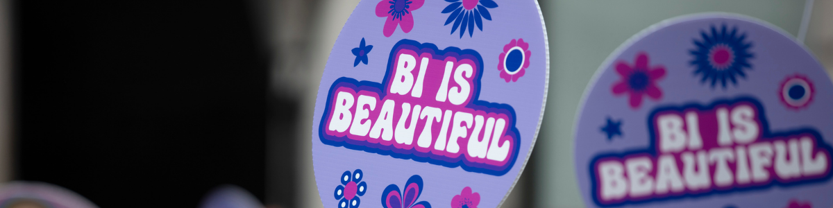 Blue, pink, and purple signs reading "Bi is Beautiful"